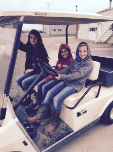 The girls having fun riding around in the old golf cart.
